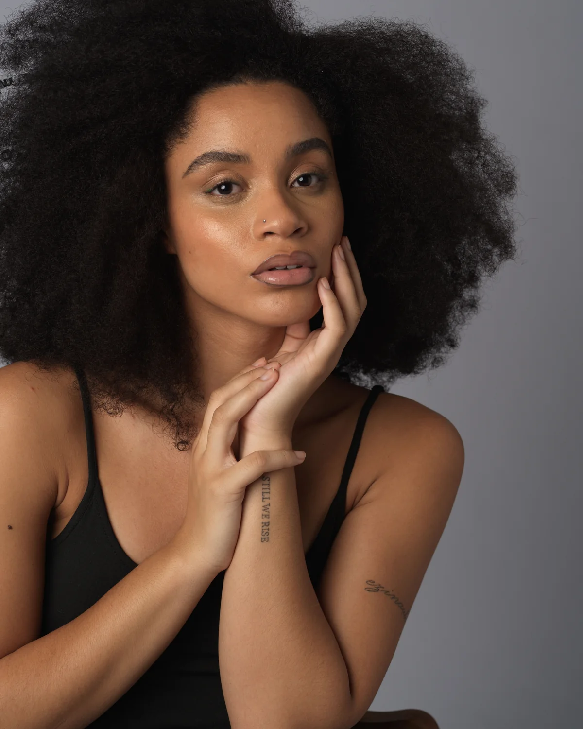 Woman with natural afro hair against a soft grey backdrop